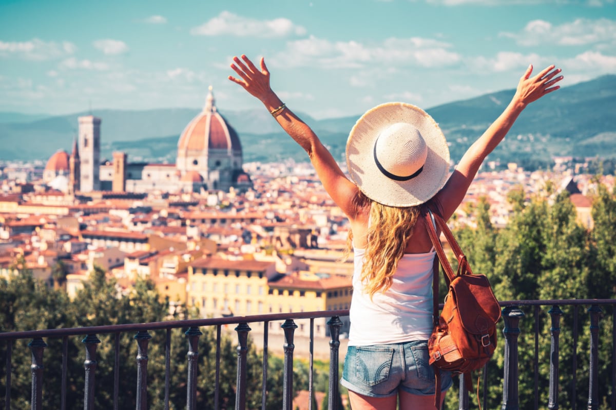woman with arms outstretched looking at florence city skyline in tuscany italy